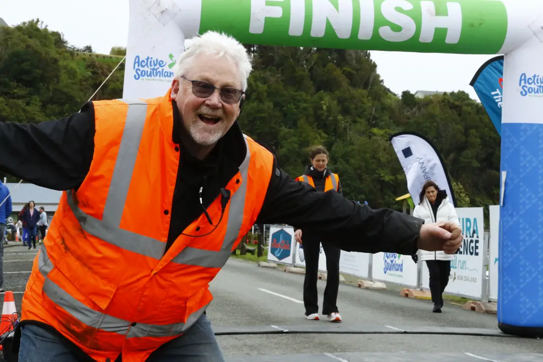 A volunteer in a hi-vis vest cheering at the finish line